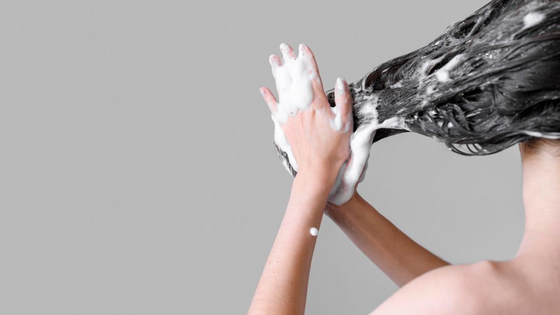Mujer lavándose el pelo con Shampoo Anticaída